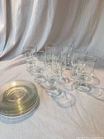 Eight footed glasses and stack of seven saucers