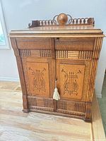 Front view of closed oak Mission-style Singer treadle sewing cabinet with carved panels and spindle gallery