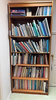 Front view of tall brown oak veneer bookcase with adjustable shelves