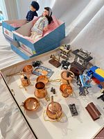 Overview of dolls in boxes with miniature cookware and sewing machines