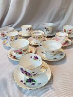 Group of 10 floral teacup and saucer sets displayed