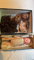 Box with dark complexion doll, wig, elastic cord, clasp, and separate box with light complexion doll
