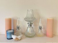 All items grouped: large oil lamp center, two small lamps, two peach pillar candles, blue hobnail jar candle