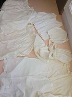 Multiple white infant garments laid flat showing quantity and variety