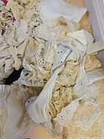 pile of assorted white and beige lace trims and fabric scraps