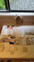 Overview of lace pieces, jars, figurines and house-shaped shelf on table