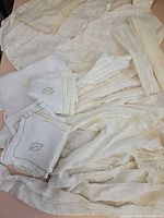 Overview of assorted white and ivory linens, embroidered napkins and blouses