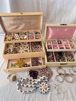Entire lot showing two jewelry boxes open with assorted jewelry spread in front