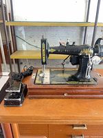 Front and side view of sewing machine with foot pedal on wood cabinet