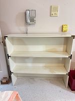 Front view of white 3-shelf bookshelf showing overall structure and wear