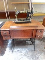 Full view of treadle sewing machine in wooden cabinet