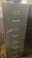 Front view of gray 4-drawer cabinet showing label frames, pulls, and lock