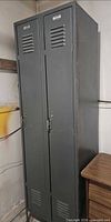 Full view of gray steel double locker showing two tall doors and overall condition
