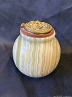 Front view of polished banded onyx jar with bronze lid