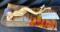 Full view of sleeping fairy on velvet pillows on wooden box base