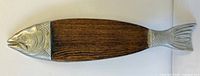 Full view of fish-shaped board showing wood body and metal head and tail