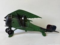 Left side view of green cast-iron biplane doorstop showing overall shape and paint
