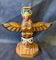 Front view of carved and painted wood totem pole on octagonal base