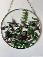 front view of circular stained glass panel showing chickadees and foliage