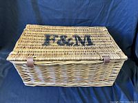Front angle of wicker hamper showing F&M monogram and leather straps