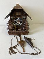 Front view of carved wood cuckoo clock with accessories
