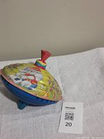 Side view of metal top showing elephant graphics, red cap, blue base
