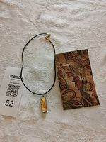 Full necklace with pendant, cord, clasp and scale reference