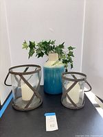 Vase with faux ivy and two lanterns side by side on tabletop