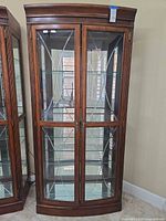 Full frontal view of cabinet showing wood frame, glass doors, shelving