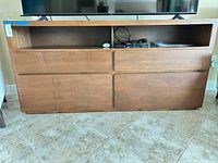 Front view of brown wood veneer media console under TV