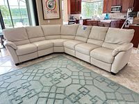 Full view of Natuzzi cream leather sectional sofa showing overall shape and seating
