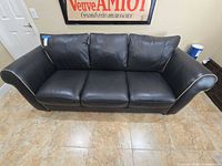 Front view of Natuzzi Larsen black leather 3-seater sofa with cream piping