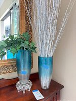 Pair of gradient glass vases on wooden surface with fillers and glass stand visible