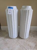 Two white ceramic textured basketweave vases side by side