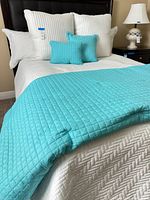 Full bed setup showing white quilted coverlet, turquoise throw, pillows