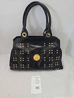 Front view of black leather Ripani handbag showing gold studs and logo medallion