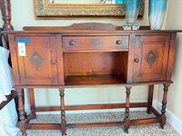 Full front view of sideboard showing doors, drawer, cubby, turned legs