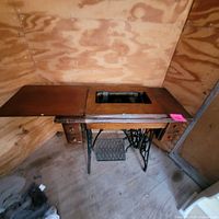 Cabinet open, showing machine stowed inside and cast-iron treadle base
