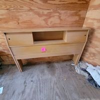 Front view of Kroehler wooden storage headboard showing three cubbies and sliding doors