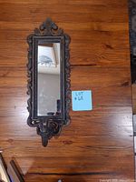 Full view of mirror sconce on wood surface