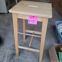 full view of stool front angle showing metal footrests and natural wood