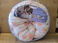 Front view of sealed Boppy Newborn Lounger package showing pillow and branding