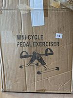Cardboard box labeled Mini-Cycle Pedal Exerciser