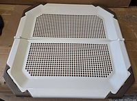 Top view of assembled potty pad holder showing mesh grate and brown corner locks