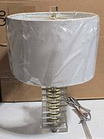 Full view of lamp with shade wrapped in plastic, base, and cord visible