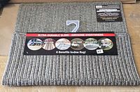 Front view of folded grey braided rug with brand header card