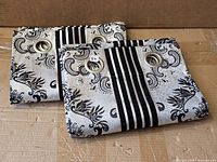 Two folded curtain panels showing pattern and grommet headers