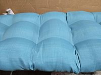 Close-up of turquoise tufted cushion surface showing fabric texture and sectioning