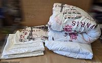 Folded comforter and folded accessory linens showing Paris print and white diamond pieces