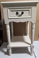 Front view of ivory accent table showing drawer, legs, shelf